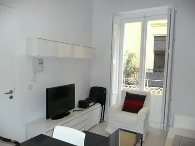 a white living room with a tv and a chair at Apartamentos Hiedra y Tapinería Mercado Central in Valencia