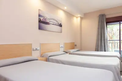 a room with three beds and a window at Hotel Olympia Ronda I in El Puig