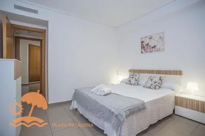 a white bedroom with a bed and a kitchen at Patacona Relax & Resort Apartments in Valencia