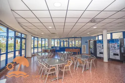 a cafeteria with tables and chairs and windows at Patacona Relax & Resort Apartments in Valencia