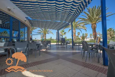 a restaurant with tables and chairs and palm trees at Patacona Relax & Resort Apartments in Valencia