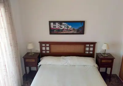 a bedroom with a bed with two nightstands and two lamps at Apartamentos Milenio in Cullera