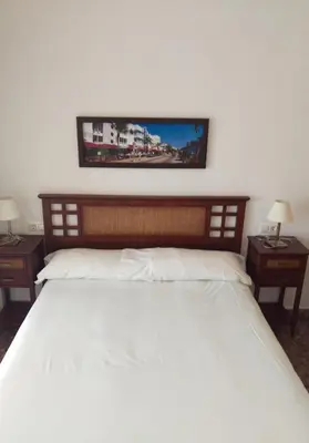 a bedroom with a large white bed with two tables at Apartamentos Milenio in Cullera