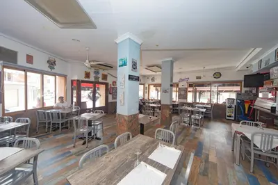 a restaurant with tables and chairs and a man sitting at a table at Hostal Virginia in Favareta