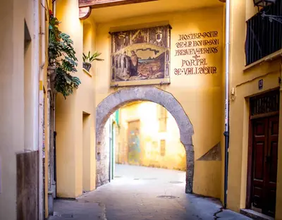 an alley in a town with a painting on the wall at Welcomer Apartments Valencia in Valencia