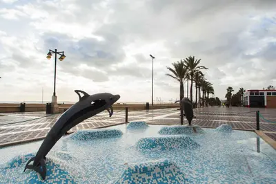 a dolphin statue in a pool next to the beach at MD Benlliure Cabañal Beach in Valencia