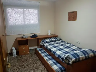 a room with two beds and a desk and a window at Pasarela Apartment in Valencia