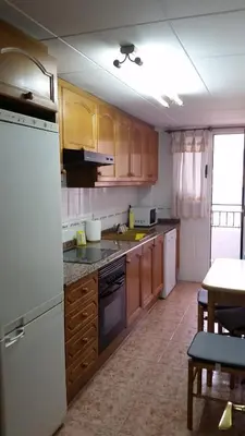 a kitchen with wooden cabinets and a white refrigerator at Pasarela Apartment in Valencia
