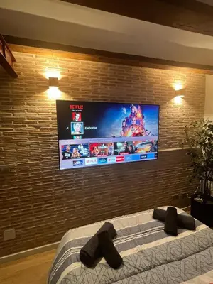a bedroom with a tv on a brick wall at Apartamentos El Olivo in Valencia