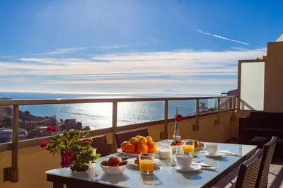 a table with fruit on a balcony with a view of the ocean at Cap Blanc Penthouse Cullera in Faro de Cullera