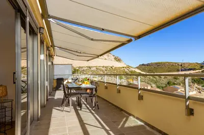 a patio with a table and chairs on a balcony at Cap Blanc Penthouse Cullera in Faro de Cullera