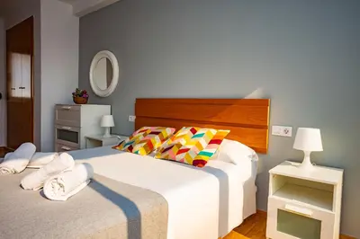 a bedroom with a large white bed with colorful pillows at Cap Blanc Penthouse Cullera in Faro de Cullera
