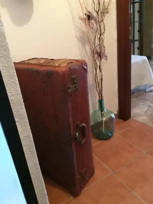 a brown suitcase sitting on the floor next to a vase at La casita Santa Bárbara in Macastre