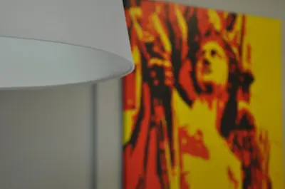 a lamp with a painting of a woman on a wall at La Casa Verde - Ruzafa in Valencia