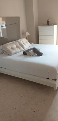 a bed with white sheets and a hat on it at Mirant el Mar in Port Saplaya