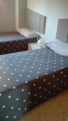 a bedroom with two beds and a table with a bedskirts at Mirant el Mar in Port Saplaya