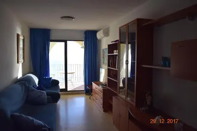 a living room with a blue couch and a sliding glass door at La Vista al mar de Belén in Port Saplaya