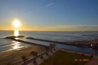 a sunset over a beach with palm trees and the ocean at La Vista al mar de Belén in Port Saplaya
