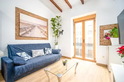 a living room with a blue couch and a window at Atico Ruzafa Valencia centro in Valencia