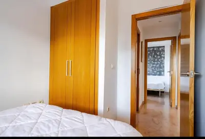 a bedroom with a bed and a wooden door at Apartamento con Vista al Mar in Tavernes de Valldigna