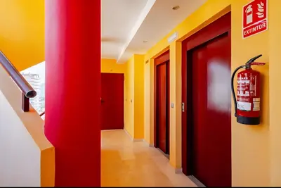 a hallway with yellow and red walls and a fire extinguisher at Apartamento con Vista al Mar in Tavernes de Valldigna