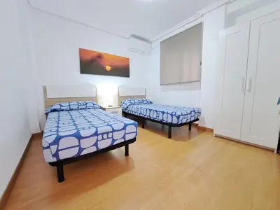 two beds in a room with wooden floors and white walls at Céntrico apartamento en Valencia próximo parada de metro Ángel Guimerà in Valencia