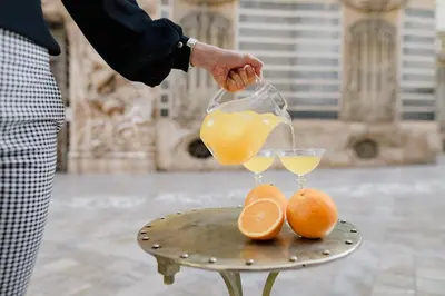 a person pouring orange juice into two glasses on a table at MYR Marqués House in Valencia