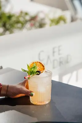 a hand holding a drink with an orange slice in it at MYR Marqués House in Valencia