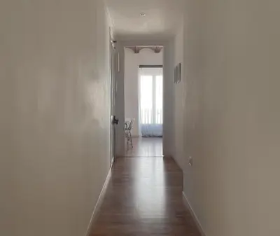 a hallway with white walls and wooden floors and a window at Calatrava in Valencia