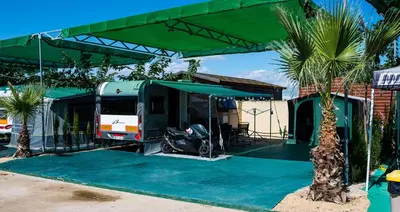 a motorcycle parked under a green canopy next to a house at Devesa Gardens in El Saler