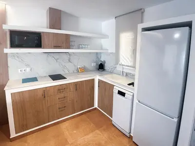 a kitchen with wooden cabinets and a white refrigerator at Devesa Gardens in El Saler