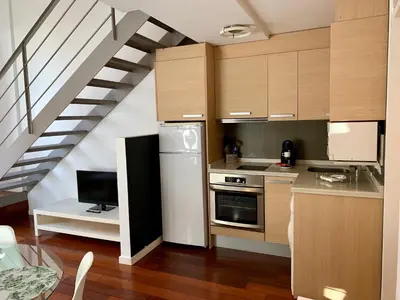 a kitchen with wooden cabinets and a staircase at Petit Palomar - PalomarGroup in Valencia