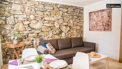 a living room with a couch and a stone wall at APARTMENTSUITESPAIN Beach Economy in Valencia