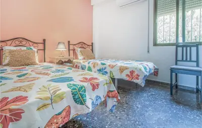 a bedroom with two beds and a blue chair at Nice Home In Alberique in Alberique