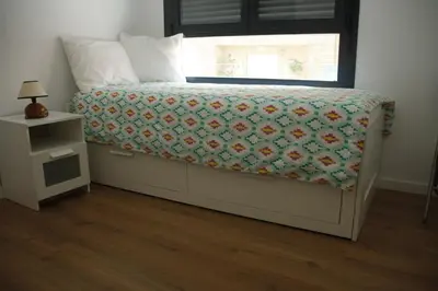 a bedroom with a bed with a flowered blanket and a window at Apartamento Ribes Valencia in Valencia