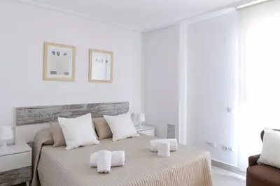 a white bedroom with a bed with towels on it at ApartUP Patacona Horizon in Valencia
