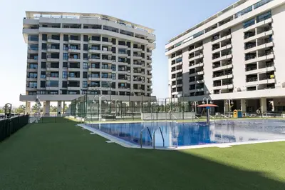 a large building with two tall buildings in the background at ApartUP Patacona Horizon in Valencia