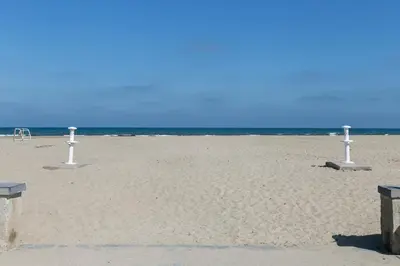 a sandy beach with three white poles in the sand at ApartUP Patacona Horizon in Valencia