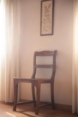 a wooden chair sitting in front of a wall at El Secanet in Algimia de Alfara