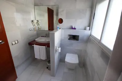 a white bathroom with a toilet and a sink at Hotel Miramar Valencia in Valencia