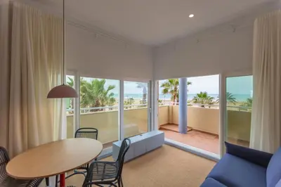 a living room with a table and chairs and a view of the ocean at Hotel Miramar Valencia in Valencia