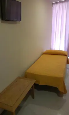 a room with a bed and a bench and a tv at Hostal Bisbal ONLY ADULTS NO AC in Valencia