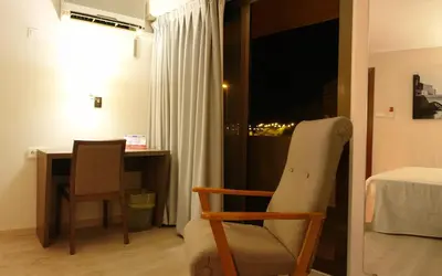 a room with a chair and a desk and a window at Hotel Avenida Plaza in Alzira