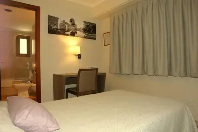 a hotel room with a bed and a desk and a bathroom at Hotel Avenida Plaza in Alzira