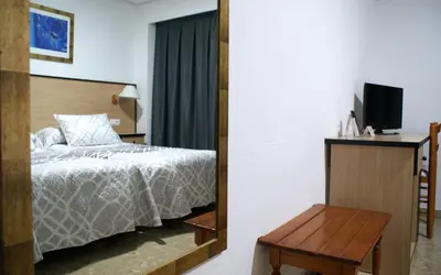 a bedroom with a bed and a tv and a table at Hotel Carabela 2 in Cullera