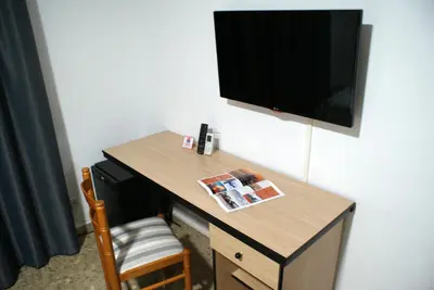 a desk in a hotel room with a television on the wall at Hotel Carabela 2 in Cullera