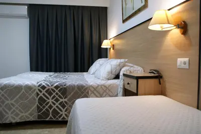 a hotel room with two beds and a table and lamps at Hotel Carabela 2 in Cullera