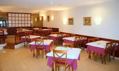 a restaurant with tables and chairs with purple table cloth at Hotel Carabela 2 in Cullera