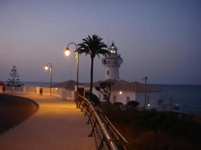 a lighthouse on the side of the ocean at night at Florazar de Ensueño in Cullera