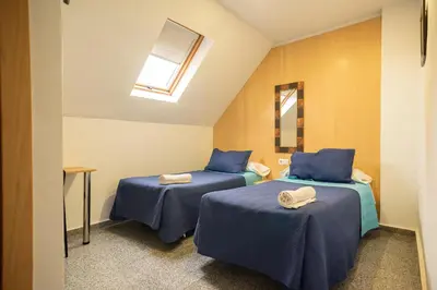a room with two beds with blue sheets and a window at Hostal Mitre Paterna in Paterna